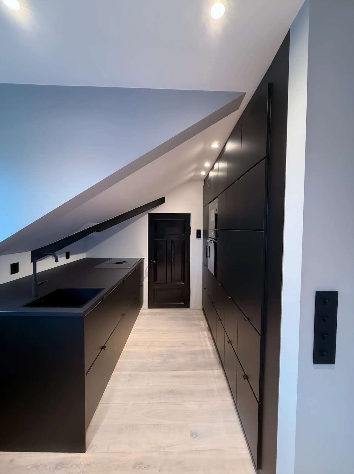 Arealeffektivt kjøkken med integrerte hvitevarer og stor benkeplate for enkel matlaging.